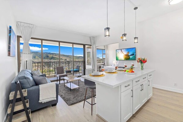 A modern living room with a sofa, coffee table, and a TV on a white island.
