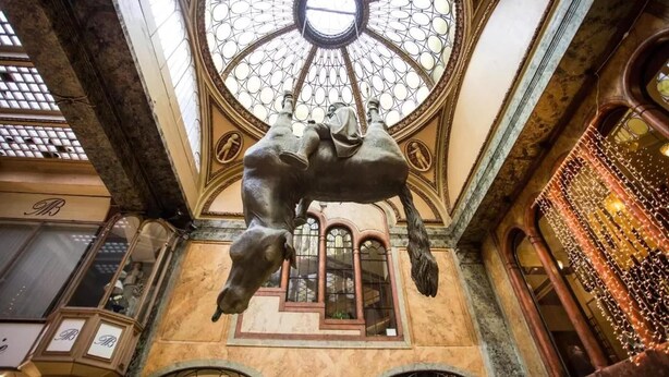 Ein prachtvoller Innenraum mit einer großen, aufwendig verzierten Kuppeldecke, einer zentralen Statue und einem detaillierten Buntglasfenster.