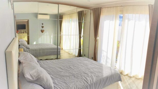 A bedroom with a large bed, a mirror, and a view of the outdoors through sheer curtains. - Escape near the sea (La Ciotat)