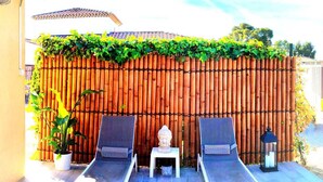 A patio with two lounge chairs, a Buddha statue, and a bamboo fence. - Escape near the sea (La Ciotat)