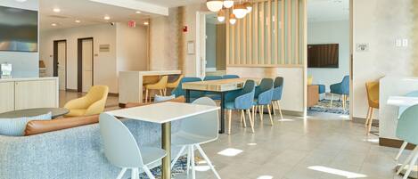Un hall d’hôtel moderne comprenant un espace repas, des coins salon et un comptoir d’accueil.