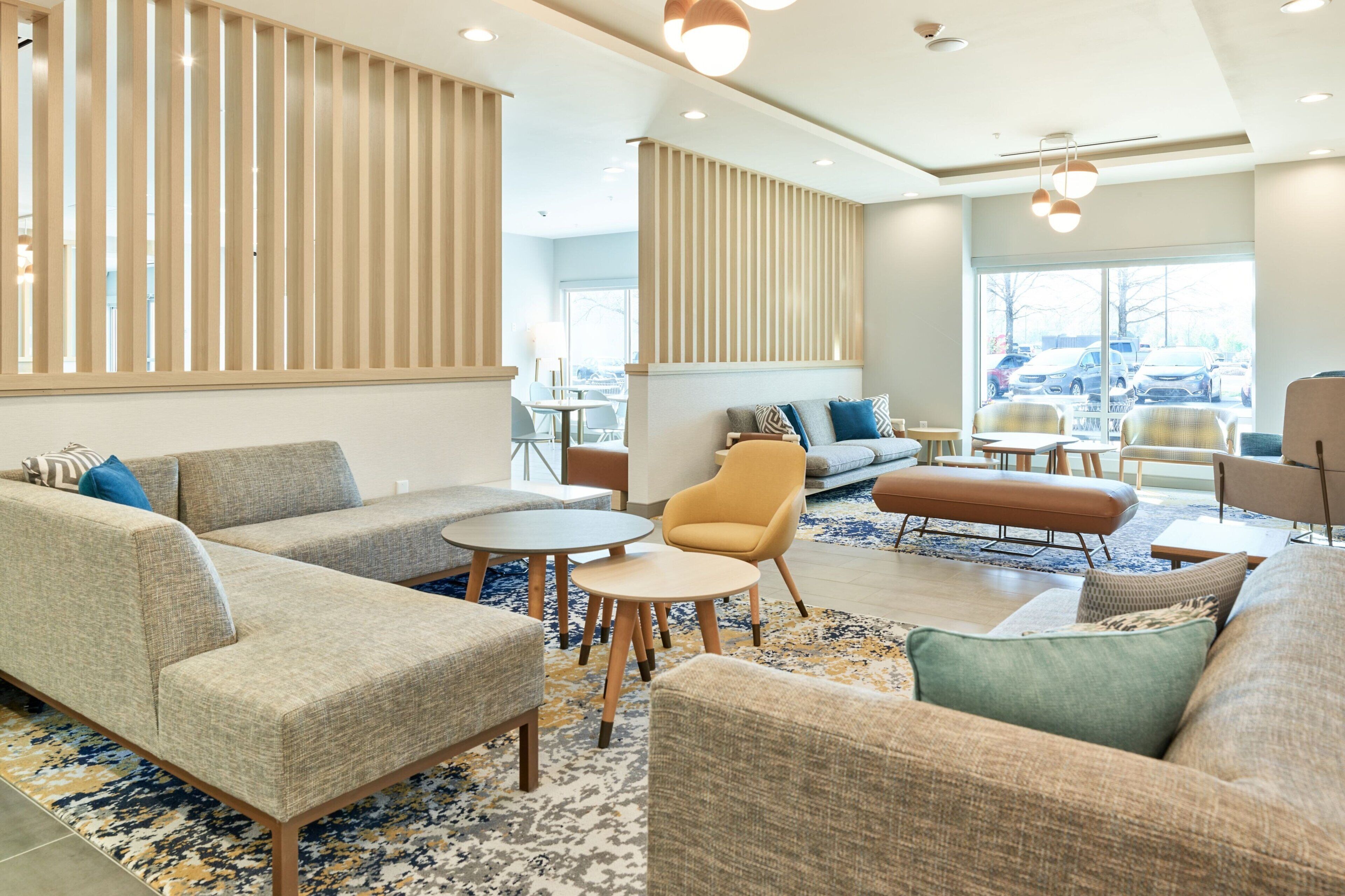 Een moderne hotellobby met banken, fauteuils en ronde tafels.