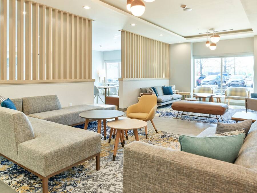 Een moderne hotellobby met banken, fauteuils en ronde tafels.