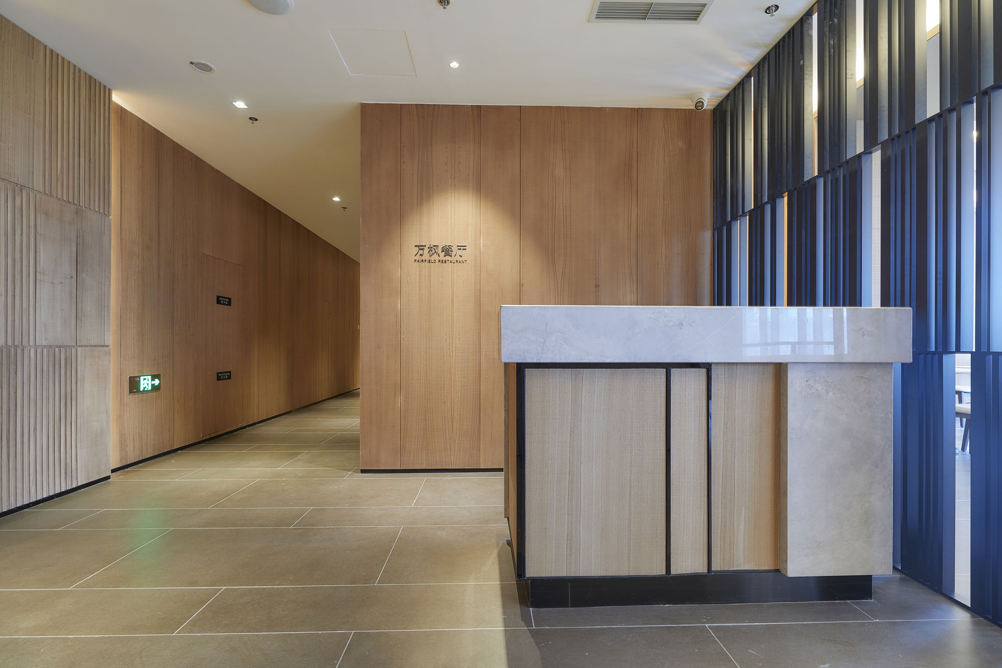 A modern reception area with a wooden panel wall, a reception desk, and a tiled floor.