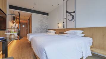 A modern hotel room with two beds, a wooden headboard, a marble wall, and a dining area with a table and chairs.