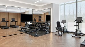 Un gimnasio moderno con cintas de correr, pesas y bicicletas estáticas.