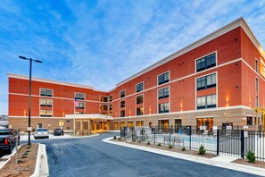 A multi-story brick building with a central courtyard, outdoor seating, and a swimming pool. - Springhill Suites by Marriott Cheraw (Cheraw)