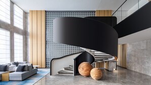 Un interior moderno con una escalera curva, un sofá modular y jarrones decorativos.