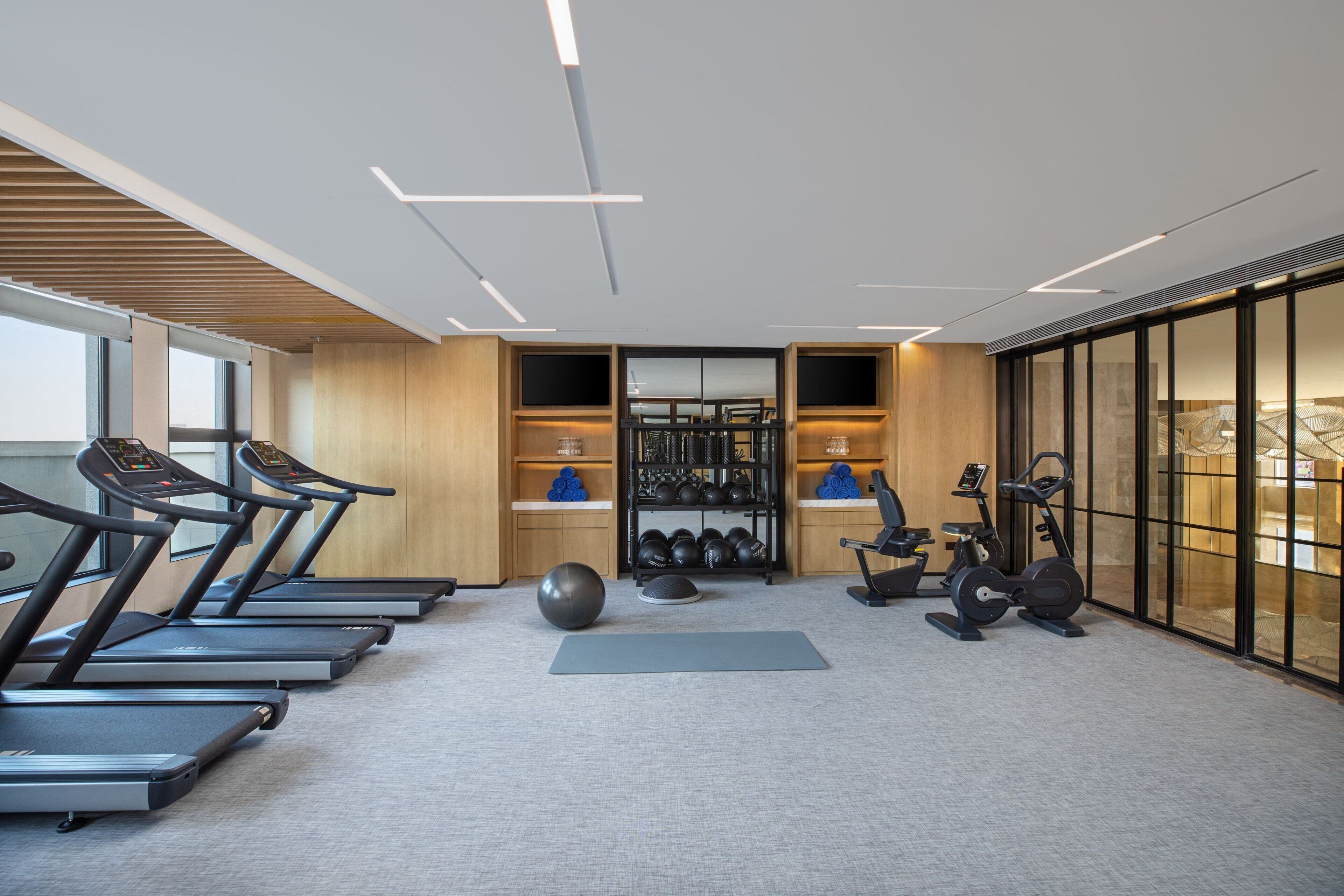 A modern gym with treadmills, exercise balls, and weight equipment.