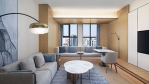 Una habitación de hotel moderna con sofá, una mesa redonda y televisor.