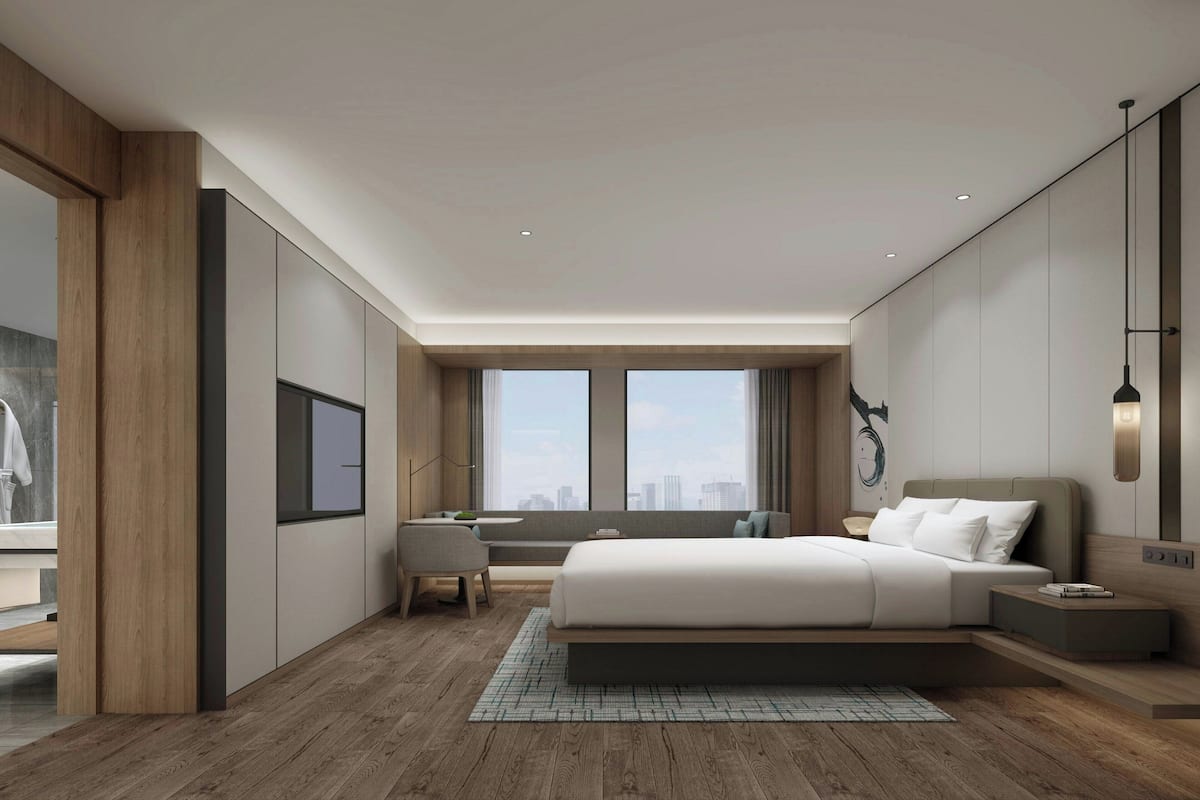 Un dormitorio moderno con una cama grande, un escritorio y vistas a la ciudad.