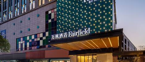 A Marriott Fairfield hotel with a large illuminated sign, a modern facade, and a landscaped entrance area.
