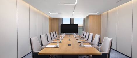 A conference room with a long table, chairs, and a projector screen.