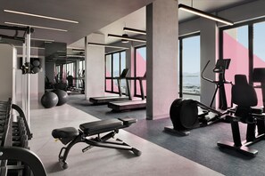 A modern gym with treadmills, elliptical machines, and weightlifting equipment.