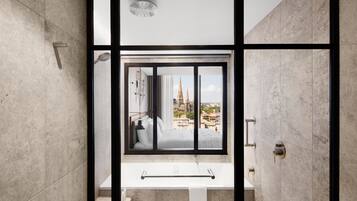 A modern bathroom with a large window, a bathtub, and a shower.