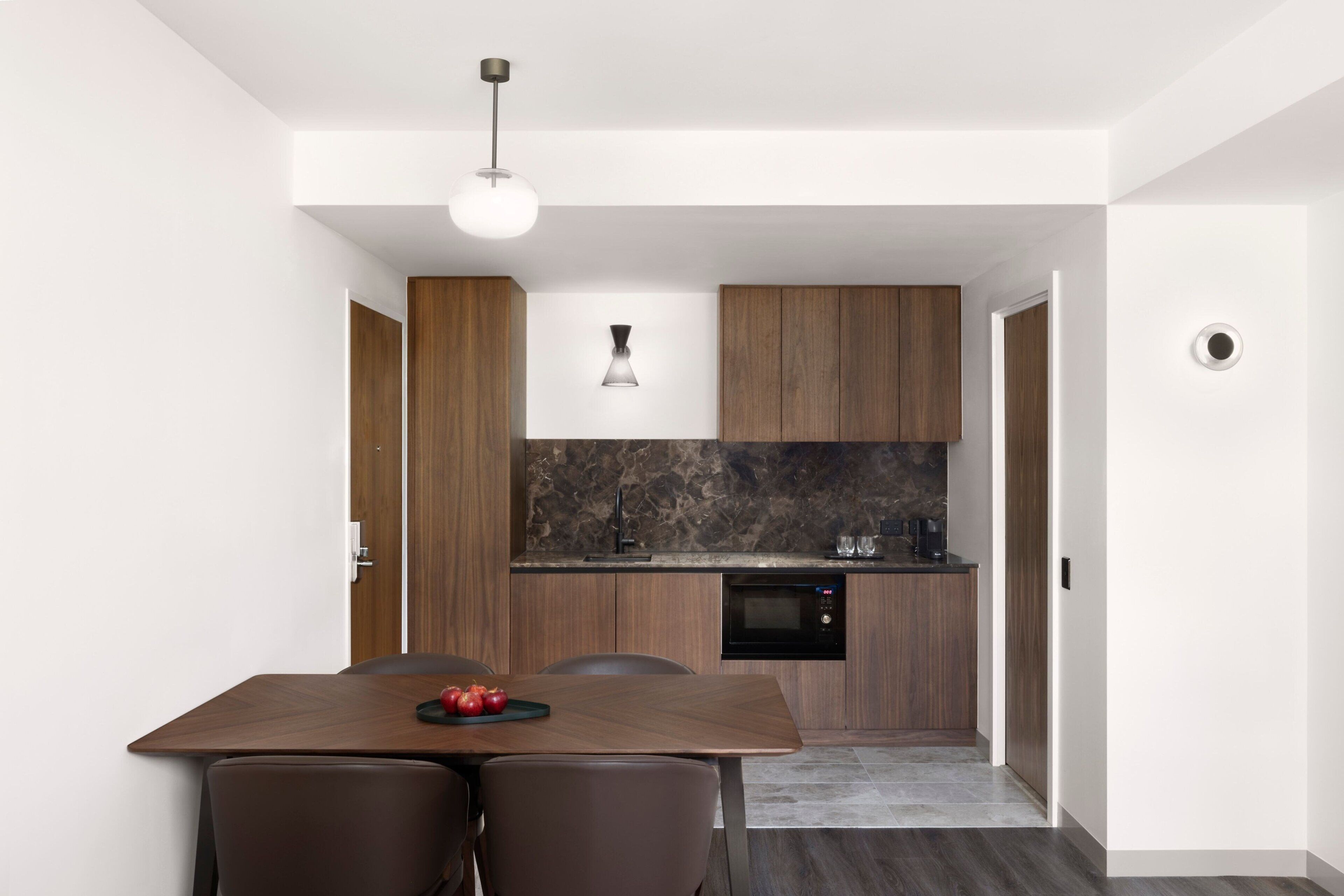 A modern kitchen with dark countertops, wooden cabinets, and a built-in oven.