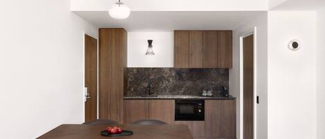 A modern kitchen with dark countertops, wooden cabinets, and a built-in oven.
