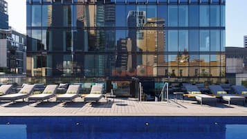 Una piscina al aire libre, sombrillas, sillones reclinables de piscina