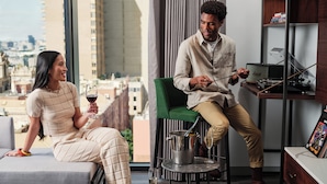 A modern living room with a city view, a green chair, a table with a book, and a wine glass. - Le Méridien Melbourne (Melbourne)
