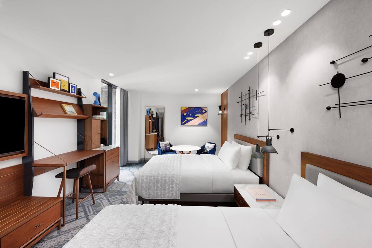 A modern hotel room with a large bed, a desk, a chair, and a TV.