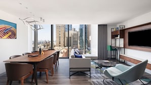 A modern living room with a dining area, a large TV, and a city view. - Le Méridien Melbourne (Melbourne)