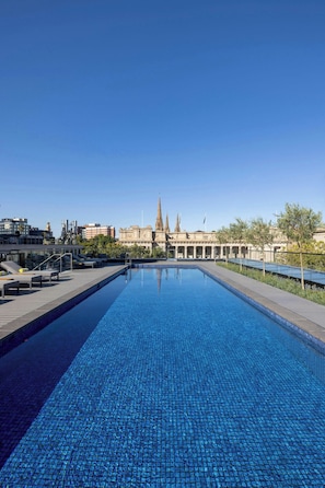 Una piscina al aire libre, sombrillas, tumbonas