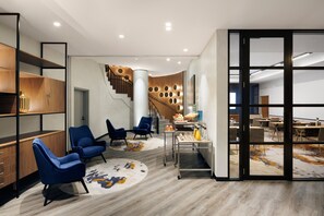Un interior moderno con escalera, sillas azules, una estación de café y un comedor.