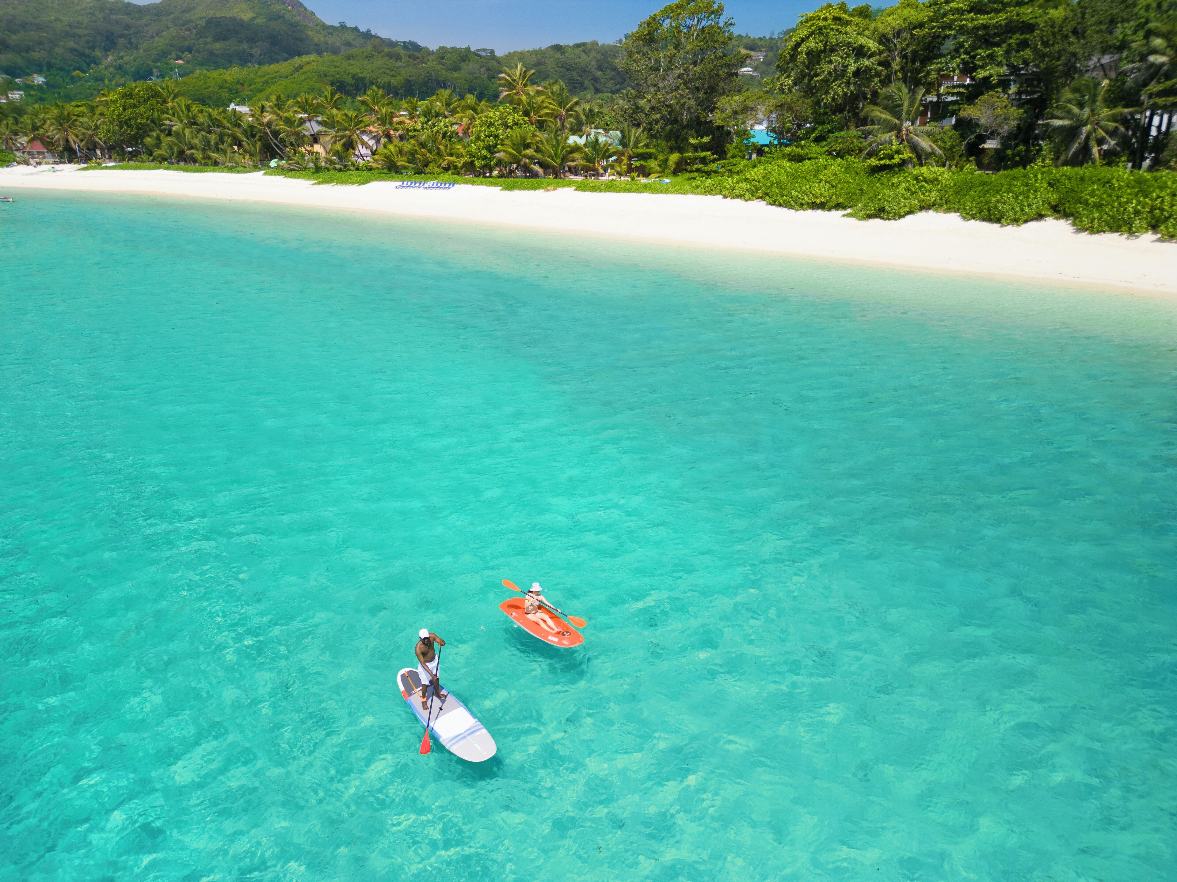 Un mar turquesa y transparente con dos tablas de paddle surf.