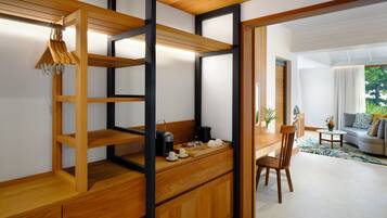 A modern kitchen with wooden cabinetry, a built-in coffee station, and a view of the living area.