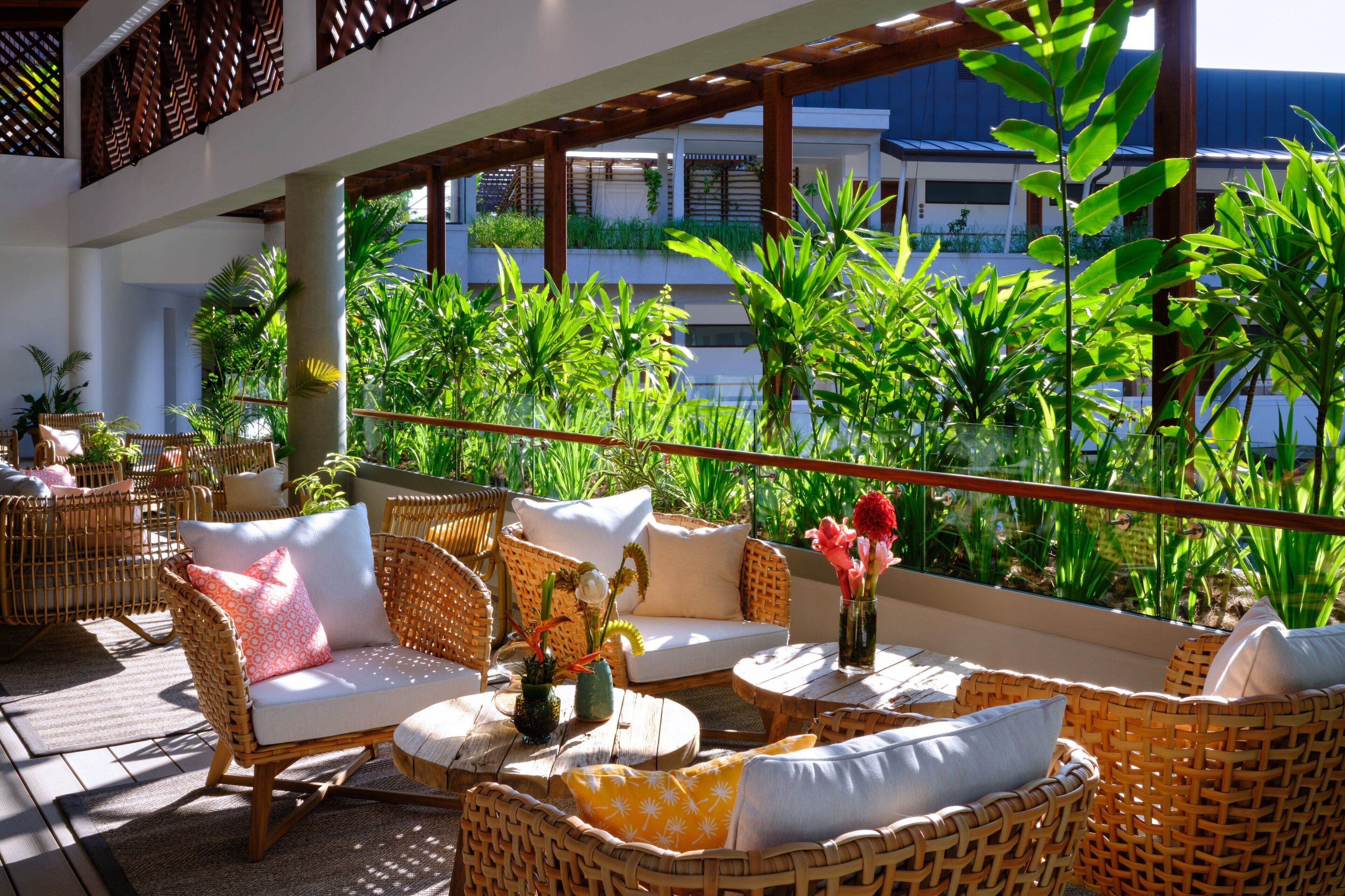 A sunlit outdoor seating area with wicker furniture and lush greenery.