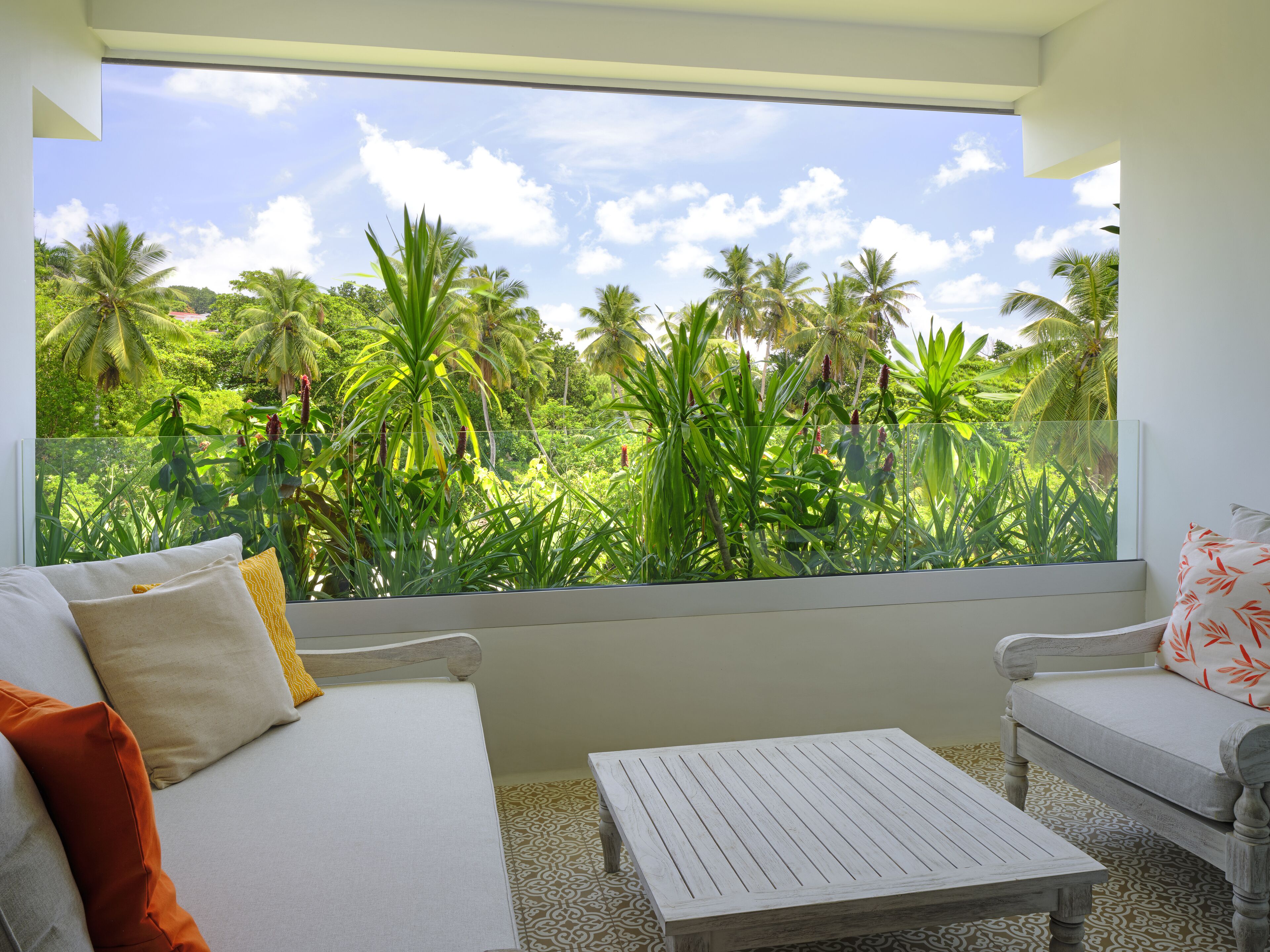Una habitación con un ventanal grande que da a un jardín tropical.