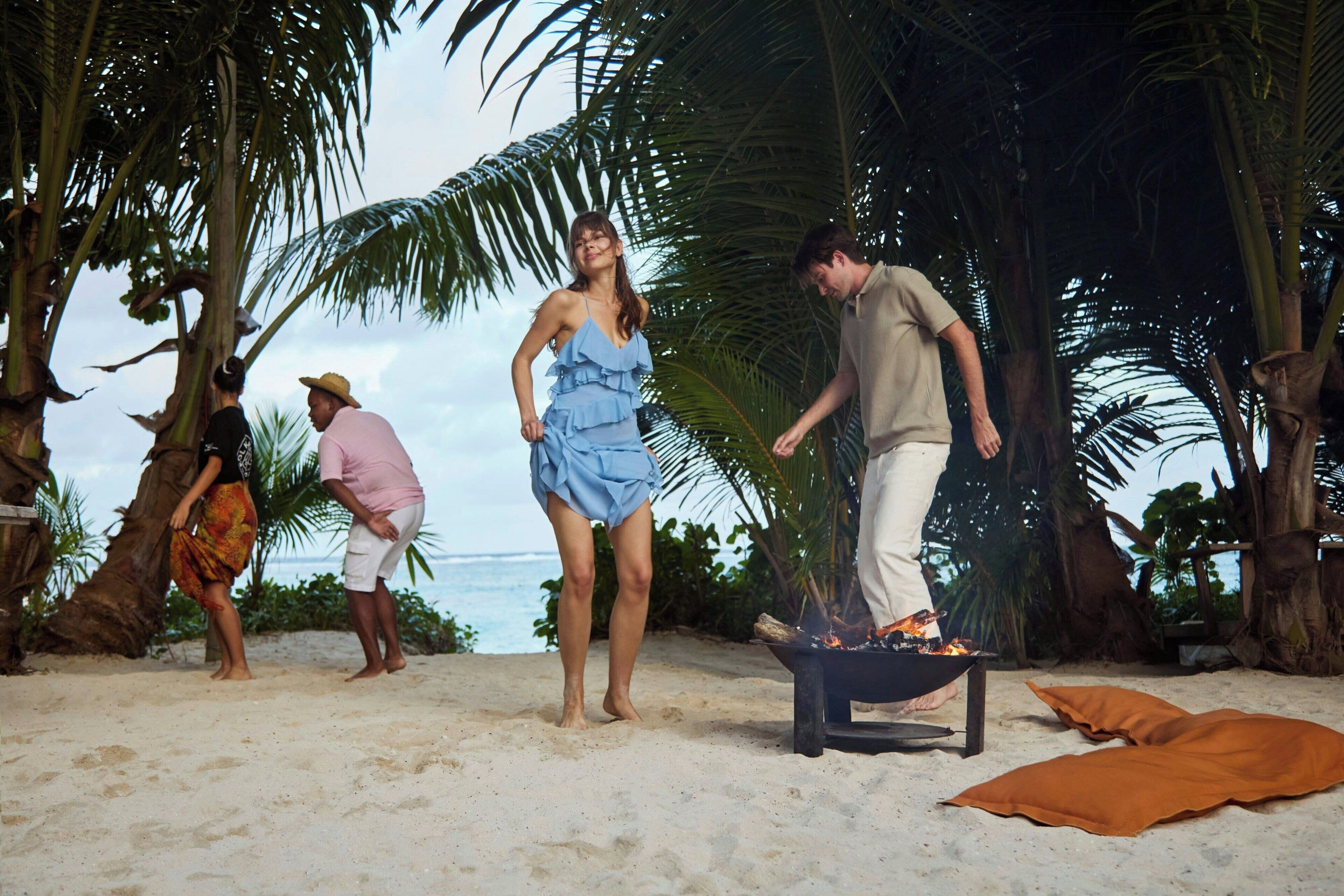 A beach scene with palm trees and a fire pit.