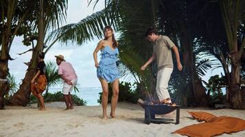 A beach scene with palm trees and a fire pit.