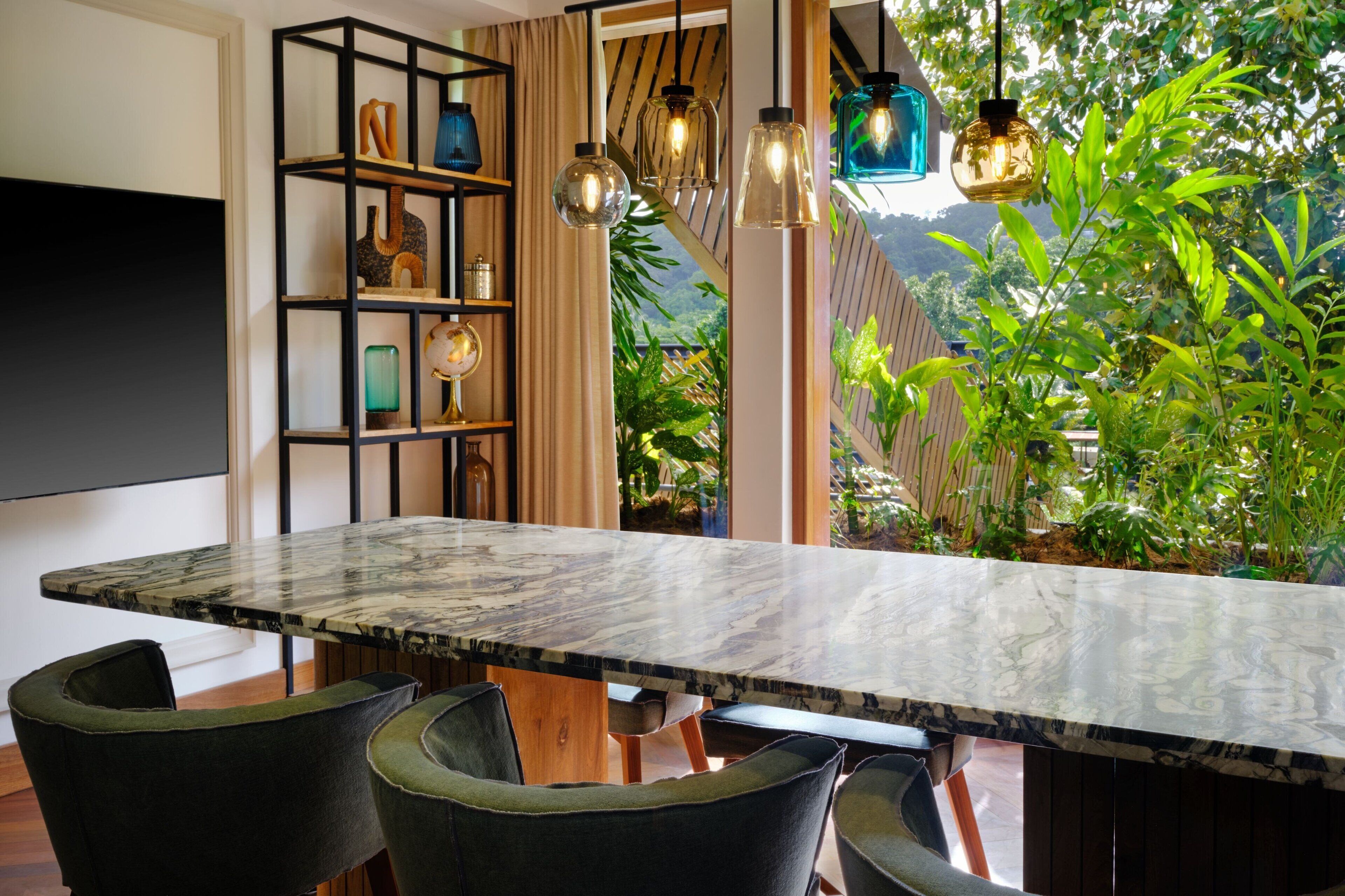 A dining area with a marble table, black chairs, a black shelving unit, and hanging pendant lights.