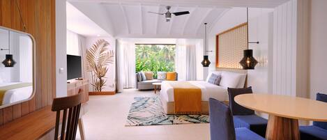 A hotel room with a bed, a dining table, a TV, and a view of greenery.