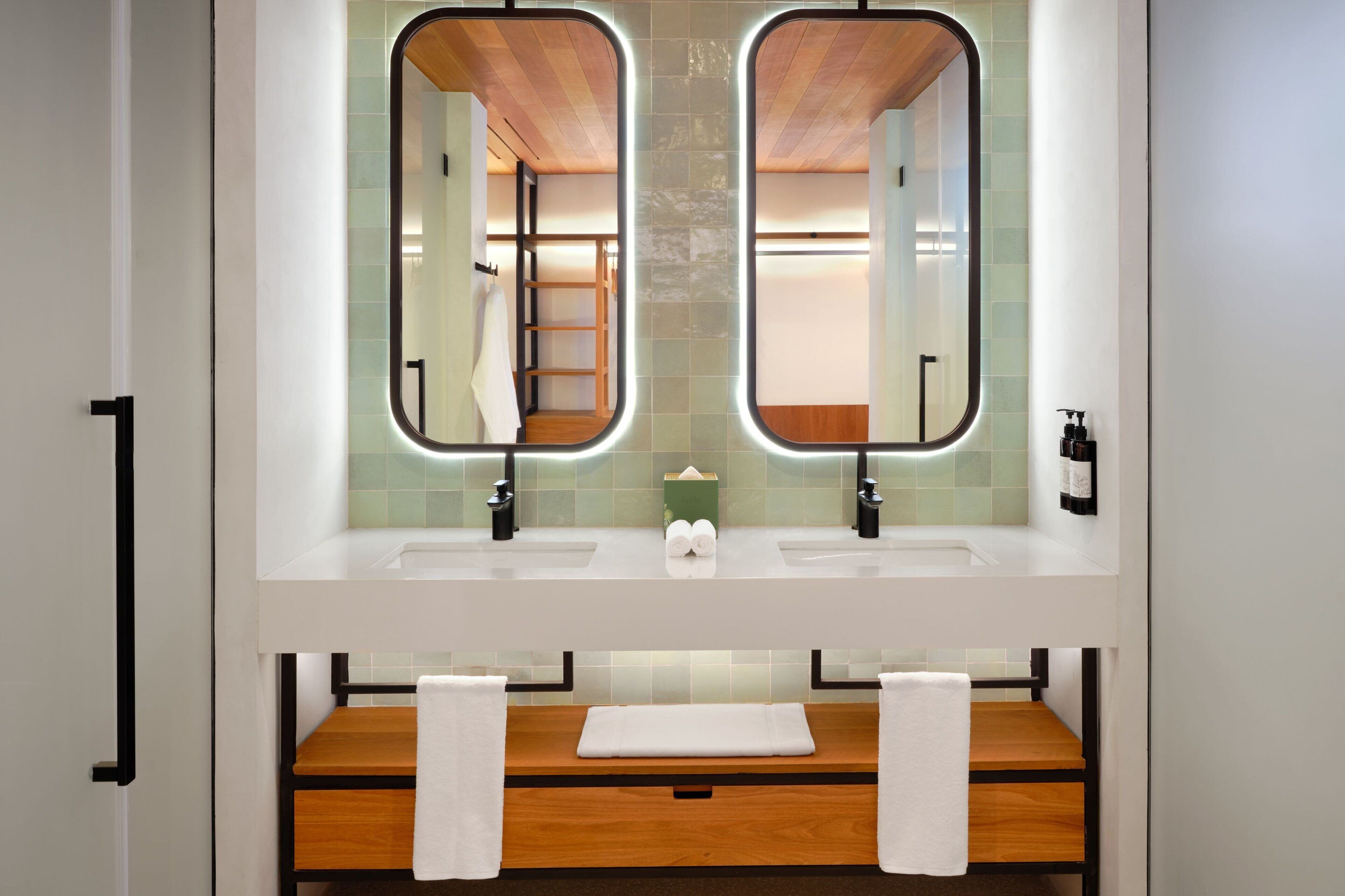 A bathroom with two sinks, a wooden vanity, and a large mirror.