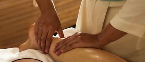 A person receiving a massage on a bed in a room with wooden paneling.