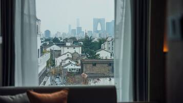 A view from a window of a cityscape with buildings and a prominent arch structure in the distance.