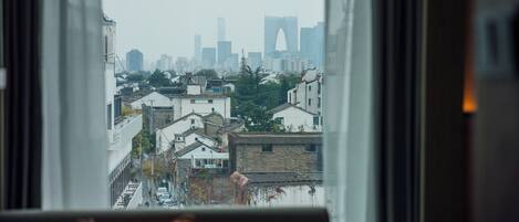 Vista desde una ventana que muestra un paisaje urbano con edificios y una estructura en arco destacada a lo lejos.