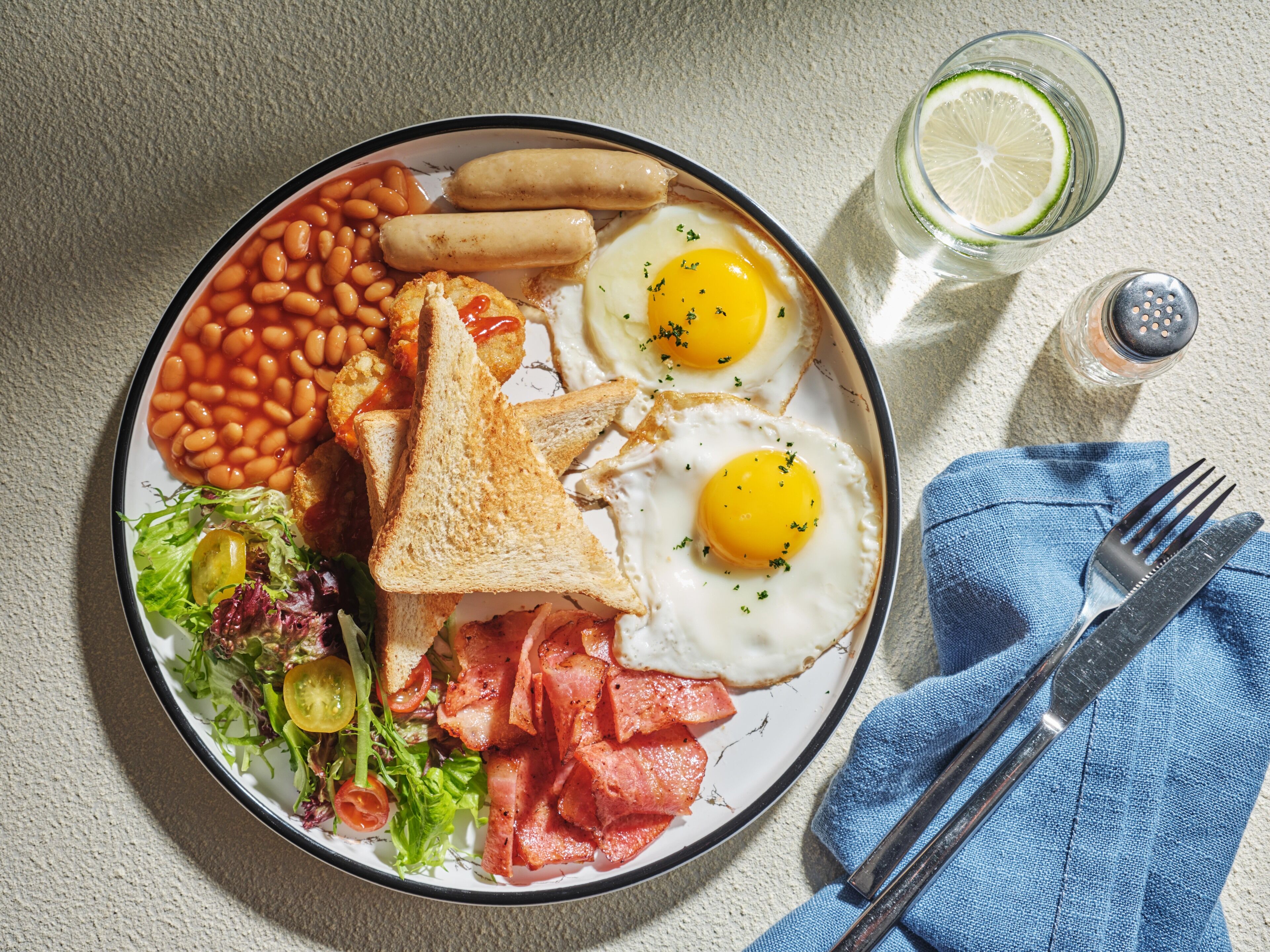 Une assiette de nourriture pour le petit-déjeuner comprenant des œufs, des haricots, du bacon et des toasts.