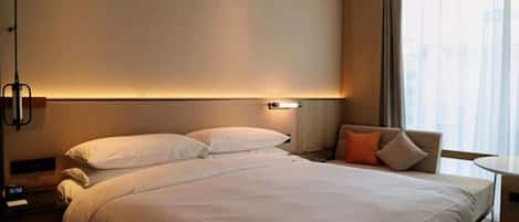 Una habitación de hotel con una cama grande, una mesita de noche, una silla y una ventana con cortinas.