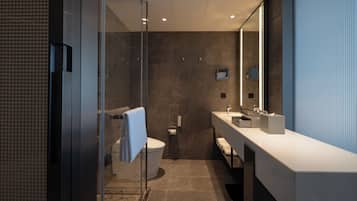Un baño moderno con cabina de ducha de vidrio, inodoro blanco y un espejo grande sobre el lavabo.