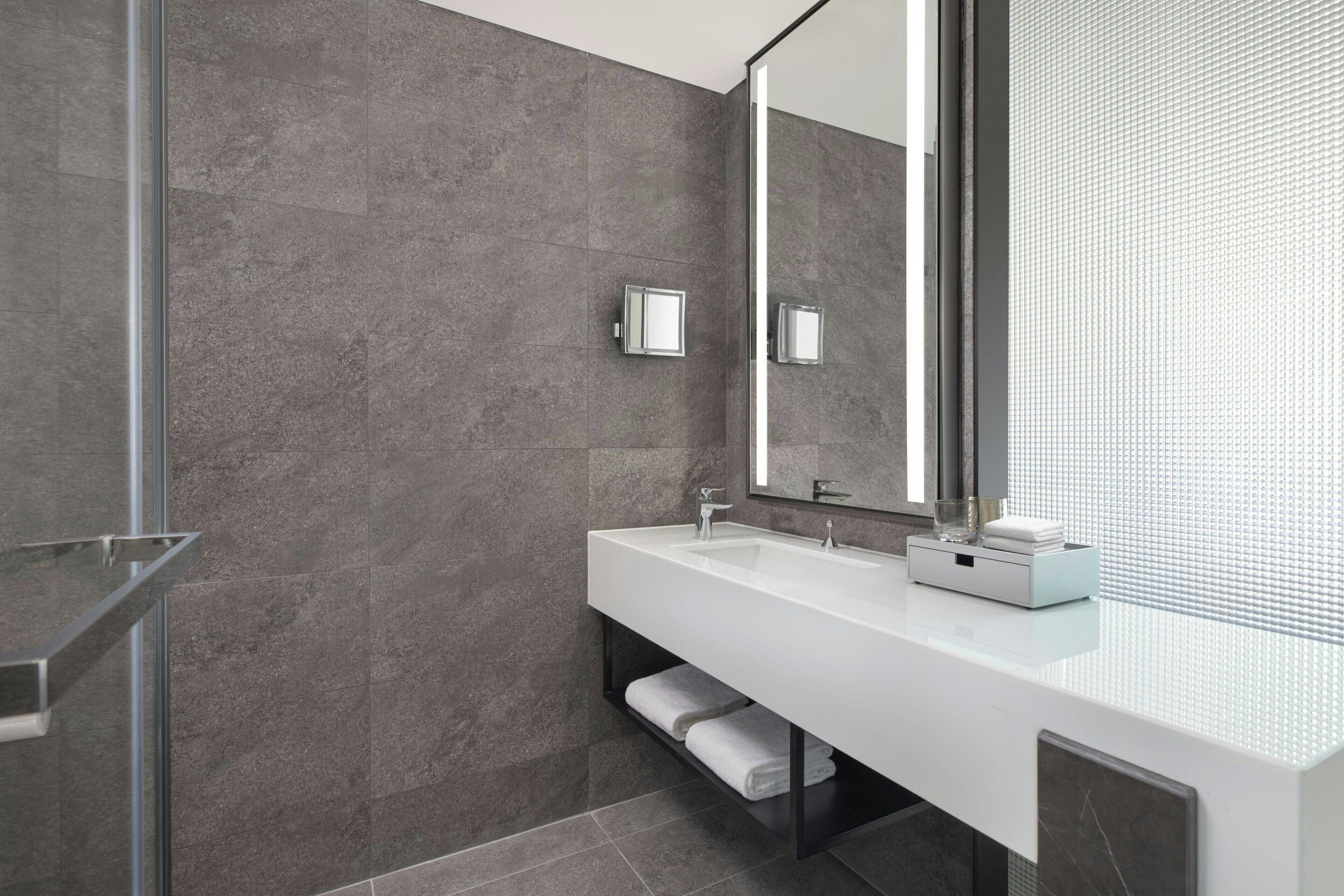 Un baño moderno con un espejo grande, dos lavamanos y una cabina de ducha de vidrio.