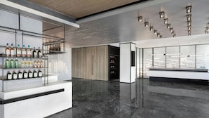 Un moderno bar con piso de mármol pulido, estantes llenos de botellas de licor e iluminación contemporánea.