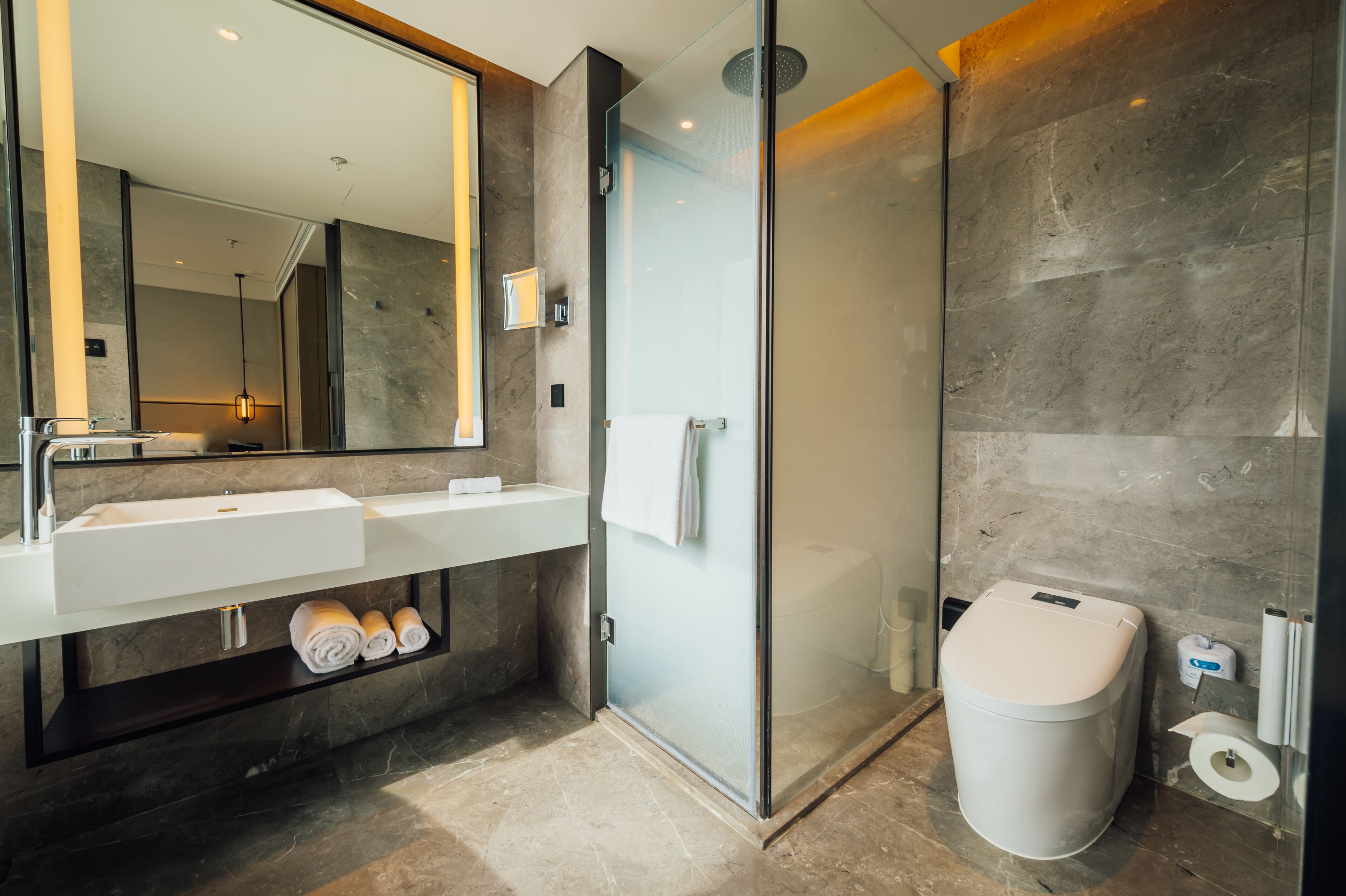 A modern bathroom with a glass-enclosed shower, a white sink, and a toilet.