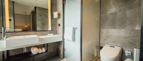 A modern bathroom with a glass-enclosed shower, a white sink, and a toilet.