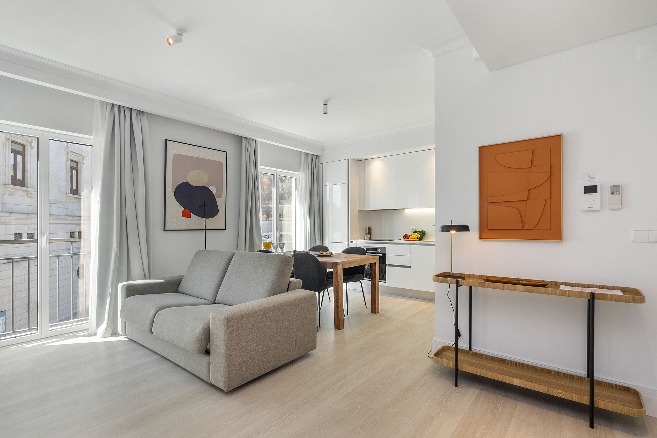 A modern living room with a grey sofa, a wooden coffee table, and a dining area with a table and chairs.
