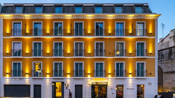 A multi-story hotel with balconies, ground-level shops, and a restaurant.