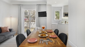 A modern dining area with a wooden table set for four, surrounded by grey sofas and chairs.
