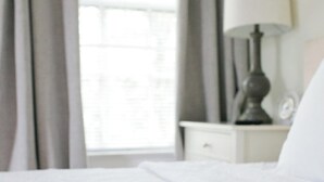 Un lit bien fait, avec une couette blanche et une couverture à motifs.